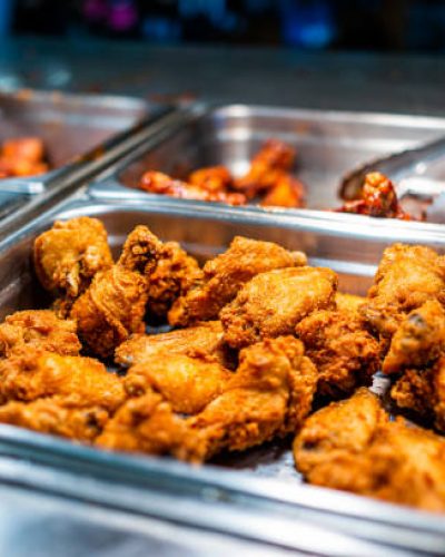 Fried chicken thighs buffet bar self serve with tongs in grocery store, restaurant or catering event with crisp skin and unhealthy food